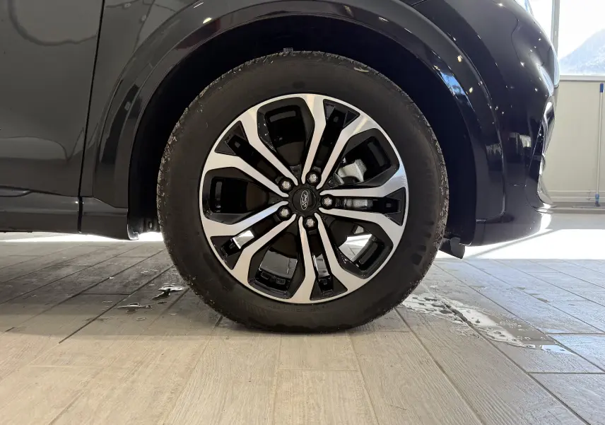 Gros plan sur la roue avant droite du Ford Puma noir Agate 2022 avec jante alliage bicolore distinctive.