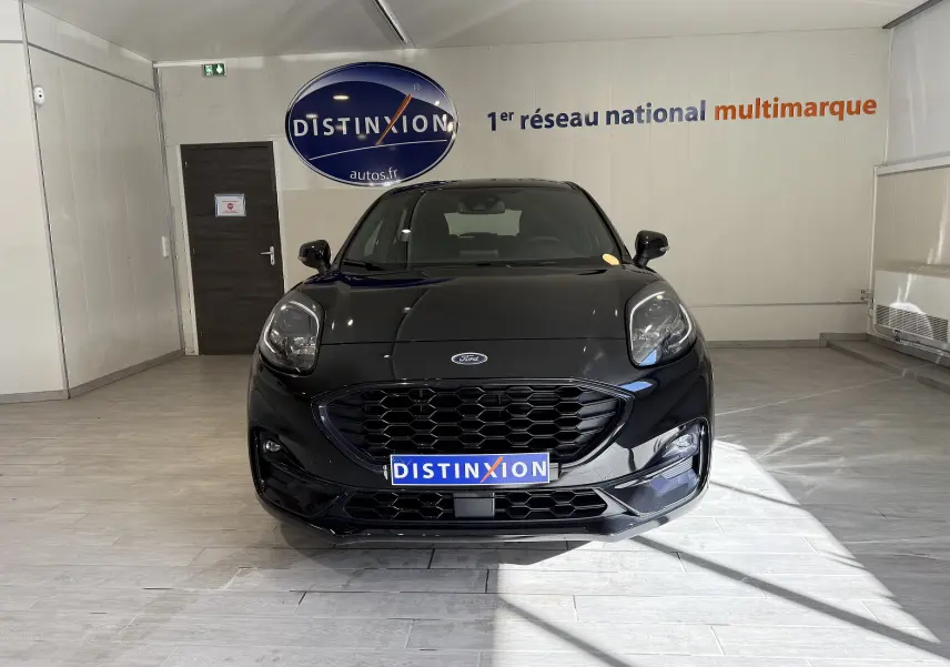 Vue de face d'une Ford Puma noire Agate 2022 en showroom avec calandre hexagonale et phares LED distinctifs.