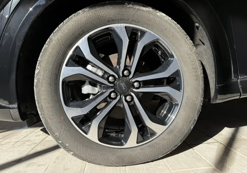 Gros plan sur la roue avant droite d'une Ford Puma noir agate, mettant en valeur la jante alliage bicolore au design moderne.