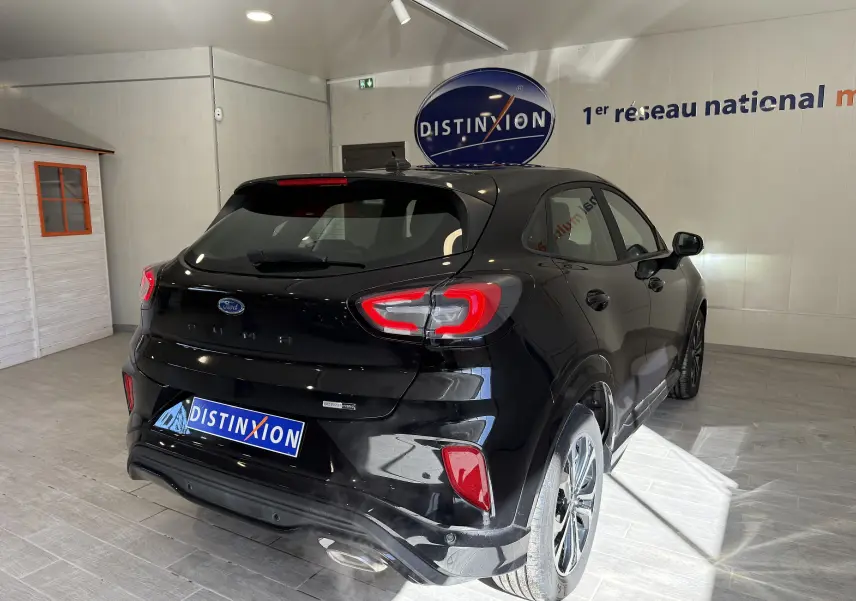 Vue 3/4 arrière droite d'une Ford Puma noire Agate 2022 avec feux arrière LED et jantes alliage en showroom.