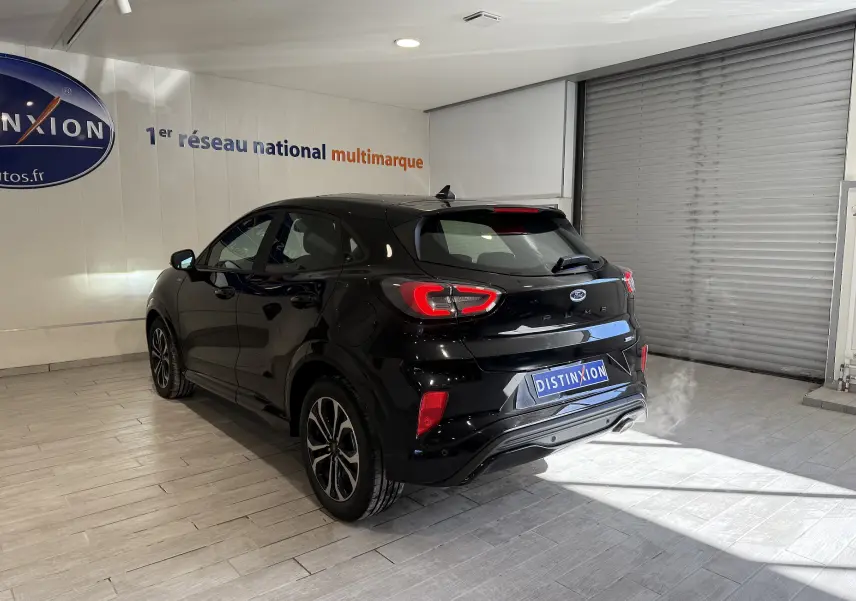 Vue 3/4 arrière droite du Ford Puma noir Agate 2022 en showroom avec feux arrière LED allumés.