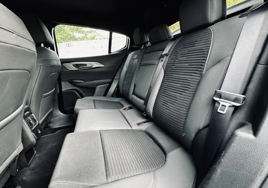 Vue intérieure côté droit de la banquette arrière noire de l'Alfa Romeo Tonale 2024 avec sellerie mixte tissu et cuir.