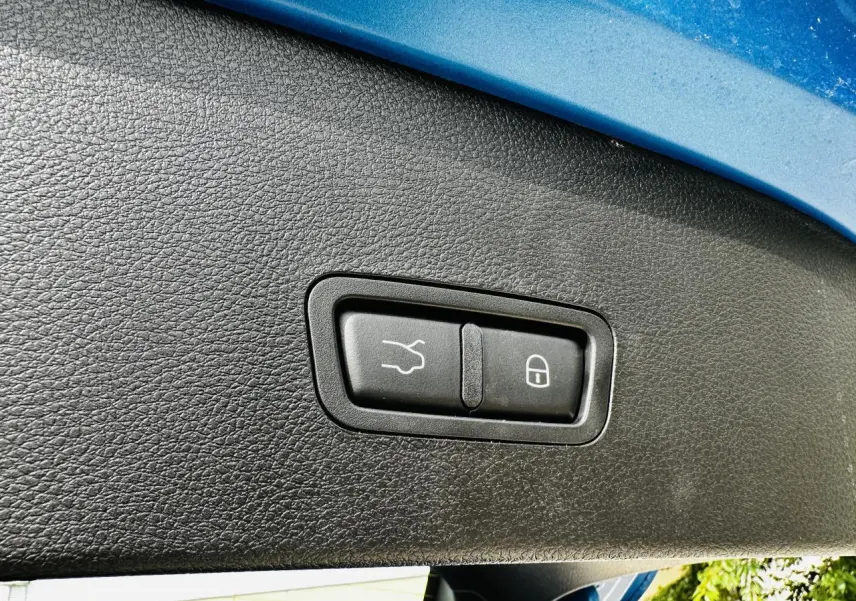 Gros plan sur les boutons de hayon électrique et verrouillage, sous l'ouverture arrière bleu métallisé d'une Alfa Romeo Tonale.