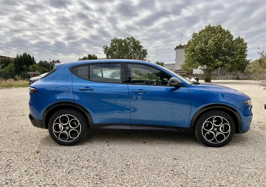 Vue latérale droite d'un Alfa Romeo Tonale bleu métallisé 2024 avec jantes distinctives à cercles entrelacés.