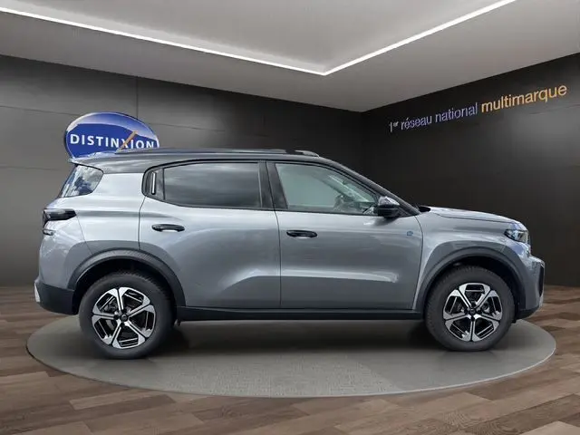 Profil droit d'un Citroën C3 Aircross électrique gris mercury avec toit noir et jantes 17 pouces en showroom.