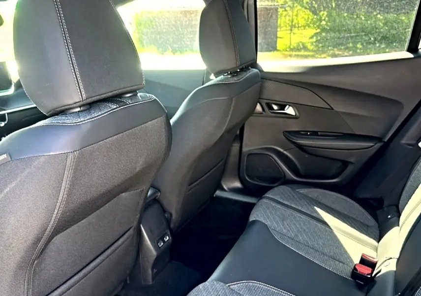 Vue intérieure arrière droite de la Peugeot 2008 1.2 100 Allure avec sièges tissu noir et gris embossé.