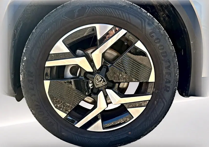 Gros plan sur la jante alu bicolore du côté gauche d’un Peugeot 2008 gris Artense, avec pneu Goodyear visible.