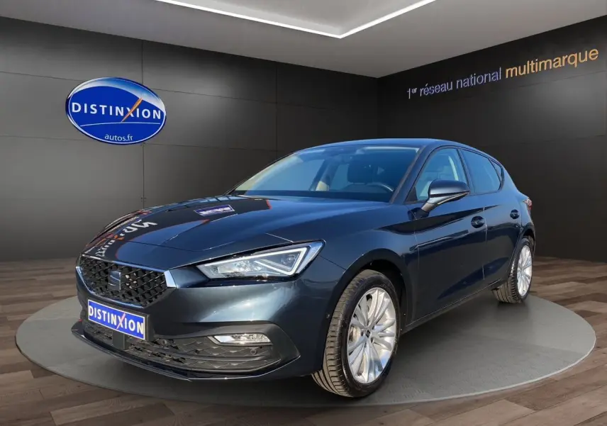 SEAT Leon gris magnetic vue 3/4 avant droit, avec jantes alu 17 pouces et phares full LED allumés.