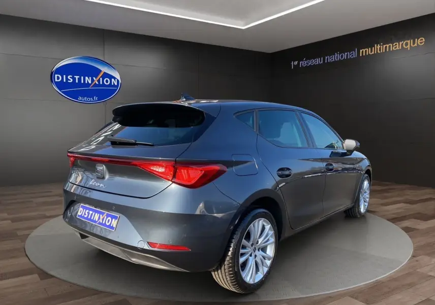 SEAT Leon gris magnetic vue 3/4 arrière droit, jantes alu 17 pouces et feux arrière LED dans showroom