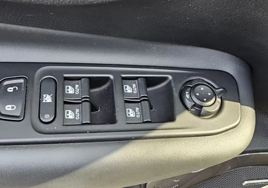 Gros plan sur les commandes de lève-vitres et réglage des rétroviseurs côté conducteur d'un Jeep Renegade Sting Gray 2020.