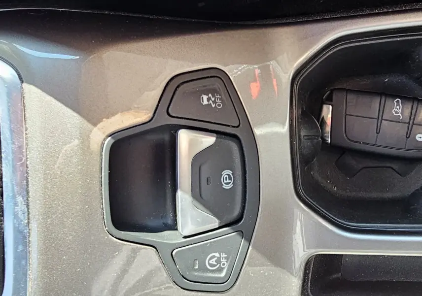 Gros plan sur la console centrale grise du Jeep Renegade Sting Gray 2020, avec frein à main électronique et clé dans le porte-gobelet.