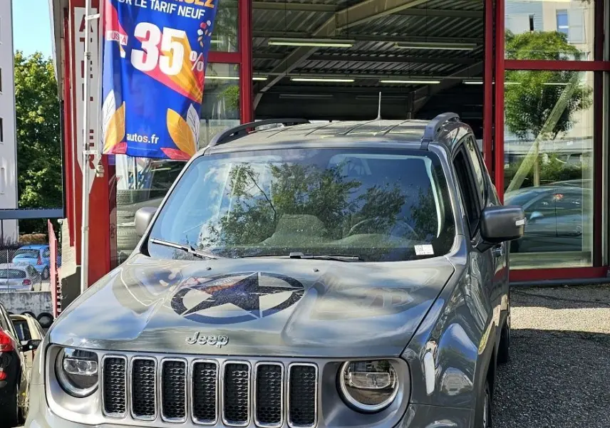 Jeep Renegade Sting Gray vue de face, avec étoile noire sur le capot, stationnée devant un garage AD Expert.
