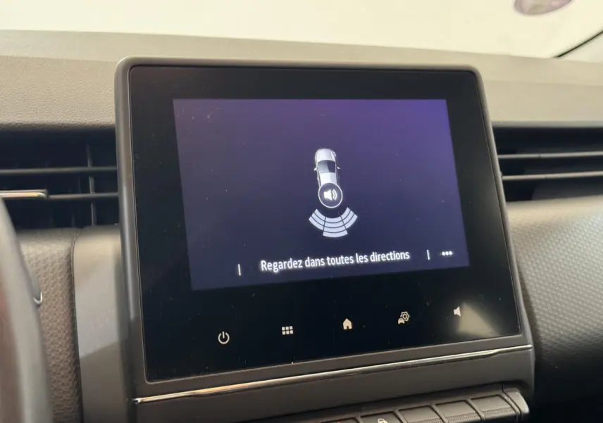 Écran tactile central affichant l'alerte de capteurs de stationnement dans l'habitacle d'une Renault Clio blanche.
