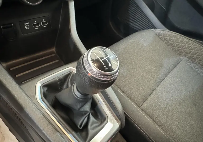 Le levier de vitesses manuel de la Renault Clio Business blanche, vu en gros plan côté conducteur avec siège gris.