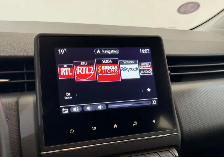 Écran tactile central affichant les radios dans l'habitacle d'une Renault Clio Business blanche, vue de face.