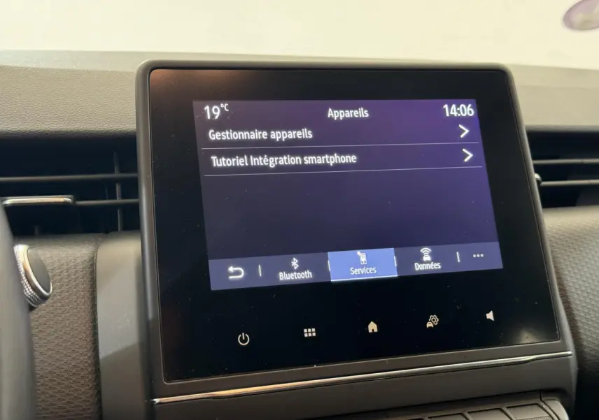 Écran tactile central affichant les options Bluetooth et services dans l'habitacle d'une Renault Clio blanche 2021.