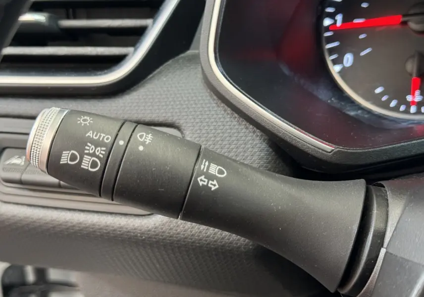 Gros plan sur la commande des phares et clignotants à gauche du tableau de bord de la Renault Clio Business blanche 2021.