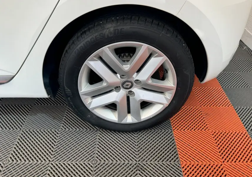 Gros plan sur la roue arrière droite blanche d'une Renault Clio Business 2021 avec jante alliage et logo Renault central.