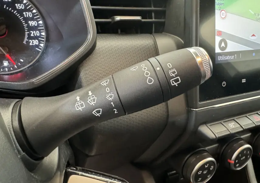 Gros plan sur la commande d’essuie-glace noire à gauche du volant dans l’habitacle d’une Renault Clio Business blanche 2021.