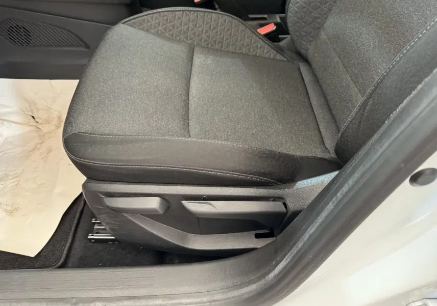 Gros plan sur le siège avant gauche gris foncé de la Renault Clio Business blanche, avec réglages manuels visibles.