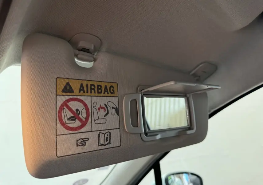 Détail du pare-soleil côté conducteur de la Renault Clio Business blanche 2021 avec miroir de courtoisie ouvert et avertissement airbag.