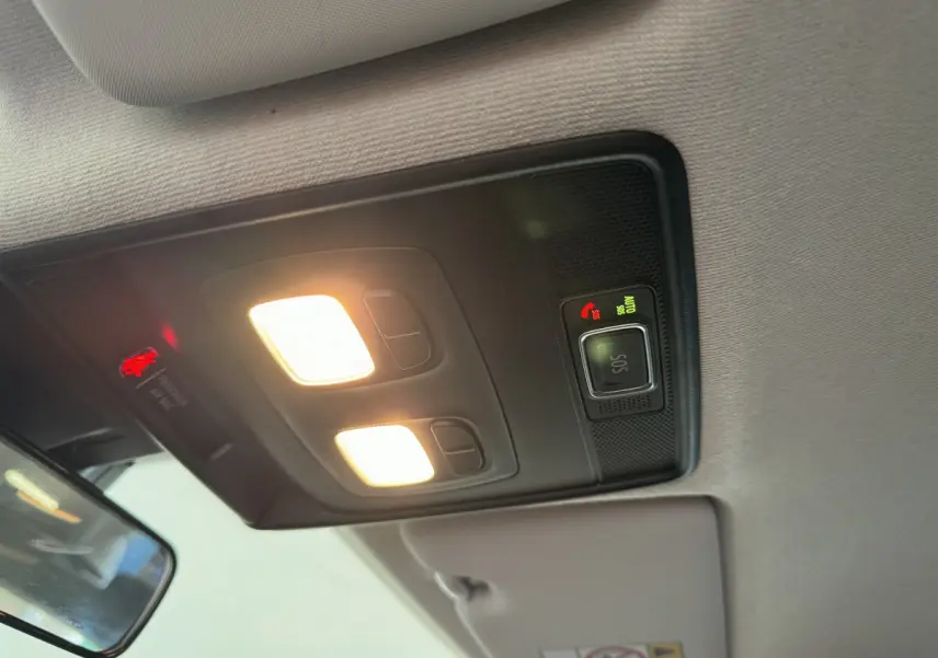 Plafonnier intérieur allumé avec bouton SOS et avertissement airbag passager sur Renault Clio Business blanc, vue vers l'avant.