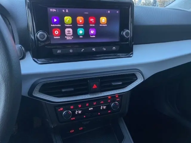 Vue rapprochée du tableau de bord de la SEAT Ibiza blanc candy 2023, avec écran tactile et commandes climatisation éclairées.