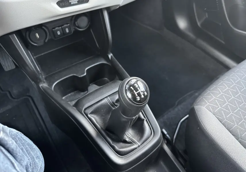 Le levier de vitesses manuel noir de la Suzuki Swift 1.2 Privilège 2025, vu en gros plan depuis le siège conducteur.