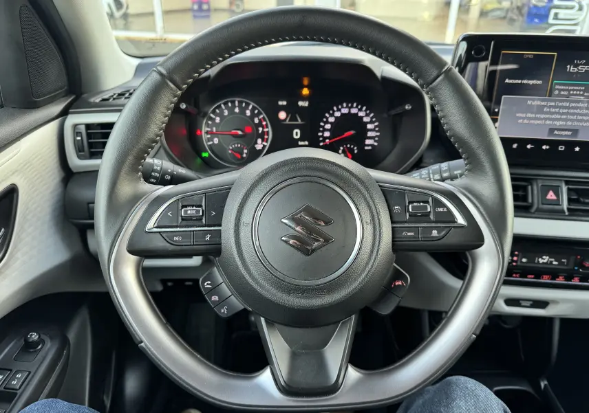Vue centrée sur le volant noir du Suzuki Swift 1.2 Privilège 2025 avec tableau de bord et écran tactile visibles.