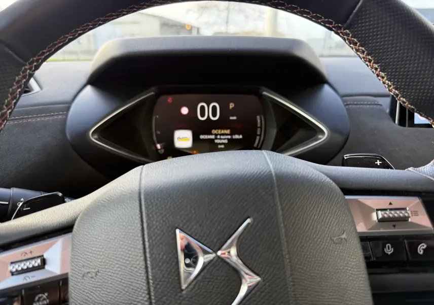 Vue rapprochée du volant en cuir noir avec logo DS et tableau de bord numérique affichant la vitesse à 0 km/h.