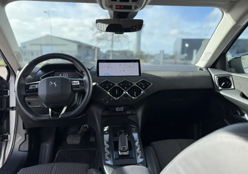 Vue intérieure avant du DS3 Hybride 2025, tableau de bord noir avec écran tactile et volant multifonction.