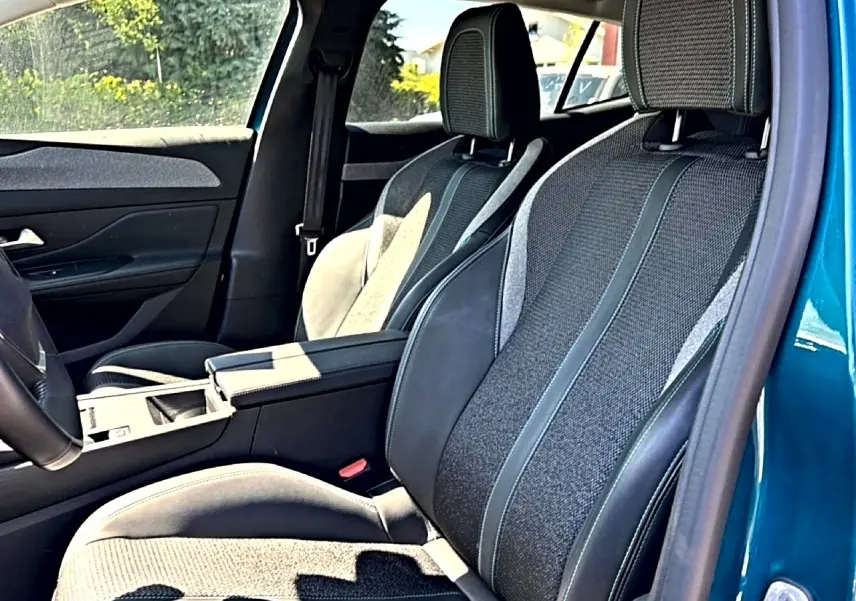 Vue intérieure côté conducteur du Peugeot 408 Hybrid 145 allure e-dcs6 bleu, sièges tissu et cuir avec accoudoir central.