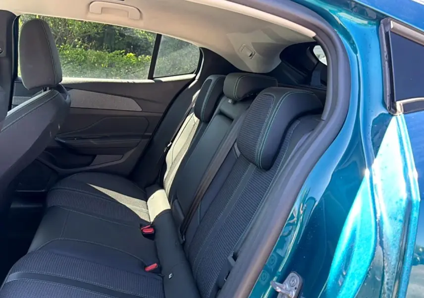 Vue intérieure côté arrière droit du Peugeot 408 Hybrid 145 allure bleu, montrant la banquette arrière en tissu et cuir.