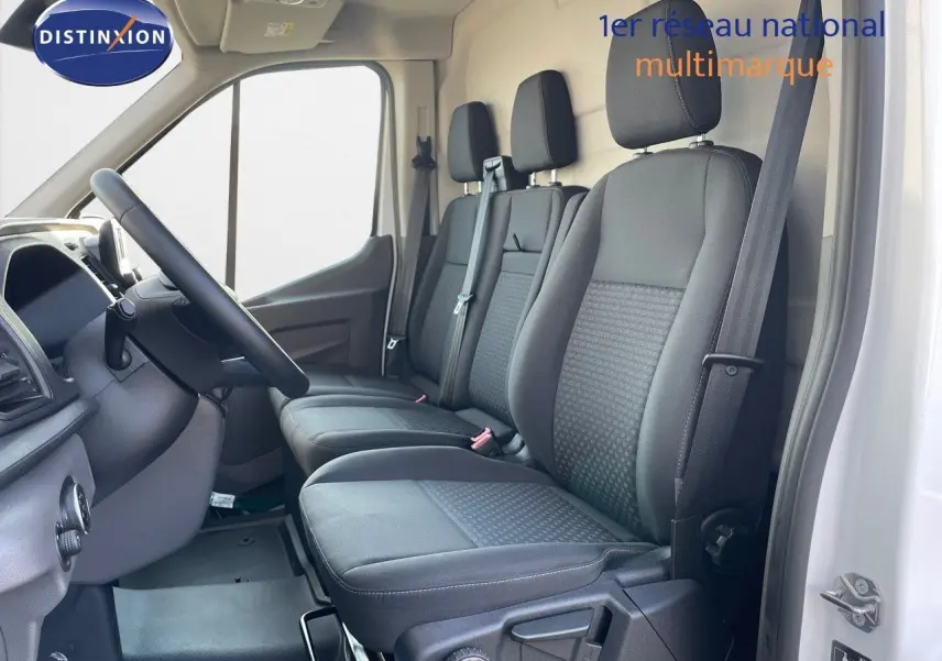 Vue intérieure côté conducteur du Ford Transit Fourgon blanc 2023, montrant les sièges noirs et le volant.