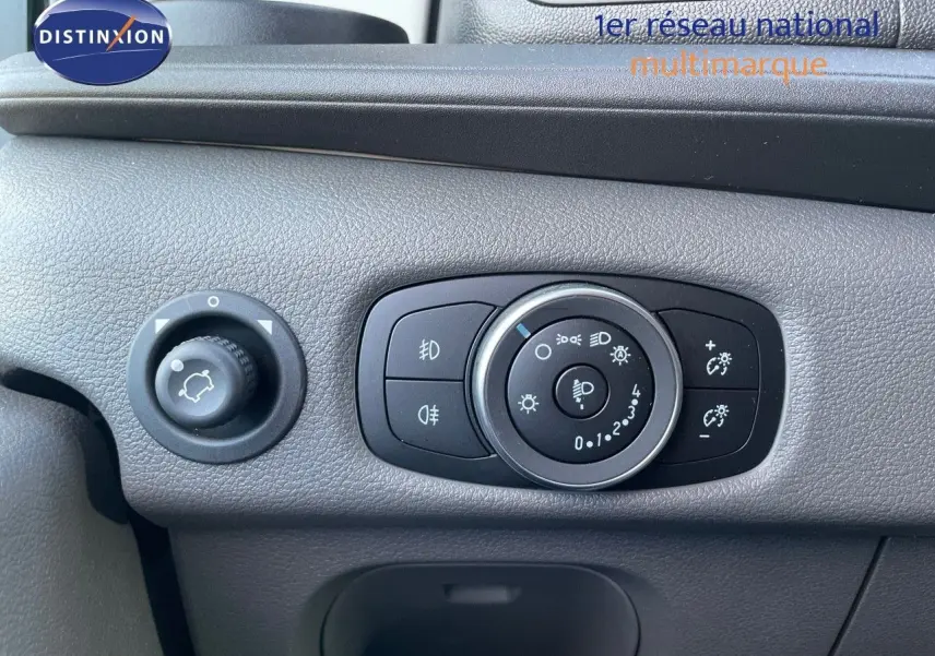 Gros plan sur le tableau de bord gris du Ford Transit Fourgon 2023 montrant les commandes d'éclairage et de réglage intérieur.