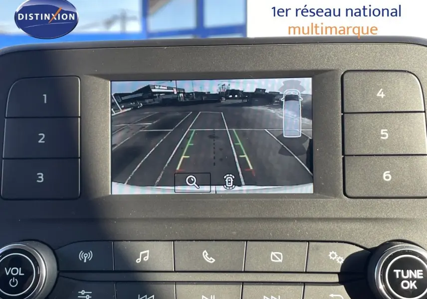 Écran de caméra de recul du Ford Transit Fourgon blanc 2023, affichant les lignes de guidage sur un parking vide.