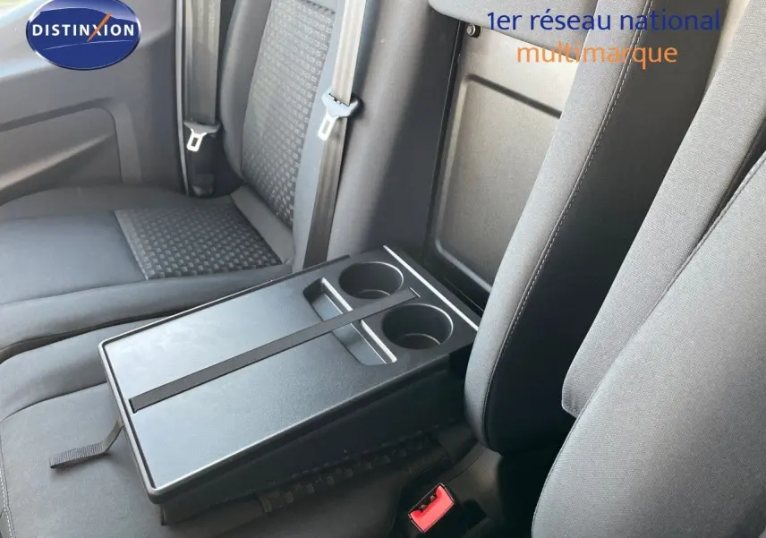 Intérieur du Ford Transit Fourgon 2023 montrant les sièges noirs et une tablette centrale avec porte-gobelets.