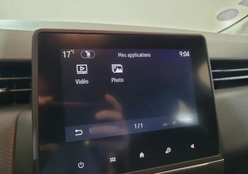 Écran tactile central affichant les applications vidéo et photo dans l'habitacle d'une Renault Clio Business blanche.