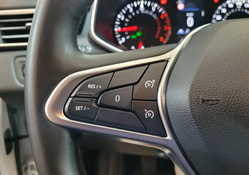 Gros plan sur le volant cuir synthétique de la Renault Clio Business blanc, avec commandes de régulateur de vitesse visibles.