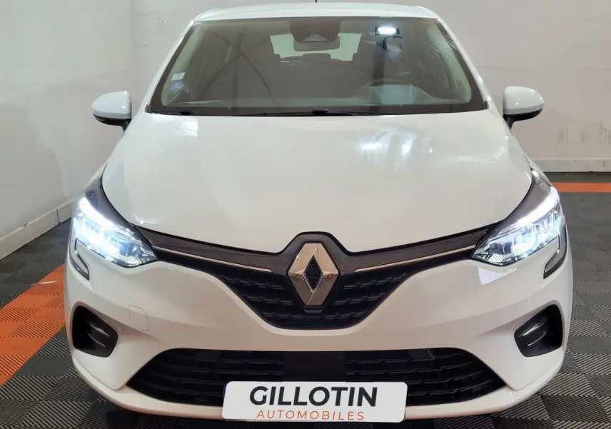 Vue frontale d'une Renault Clio Business blanche avec phares LED allumés et calandre noire distinctive.