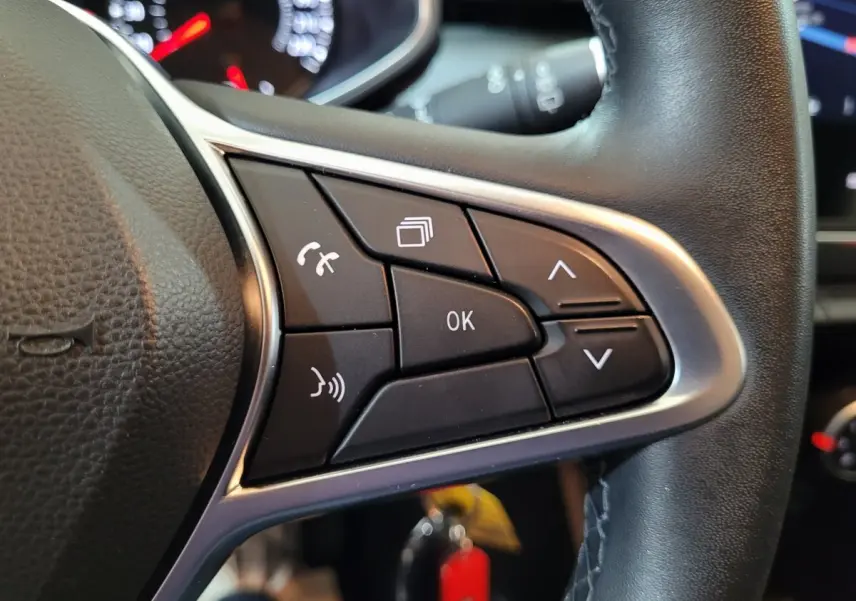 Gros plan sur les commandes multifonctions du volant cuir noir de la Renault Clio Business blanche de 2021.