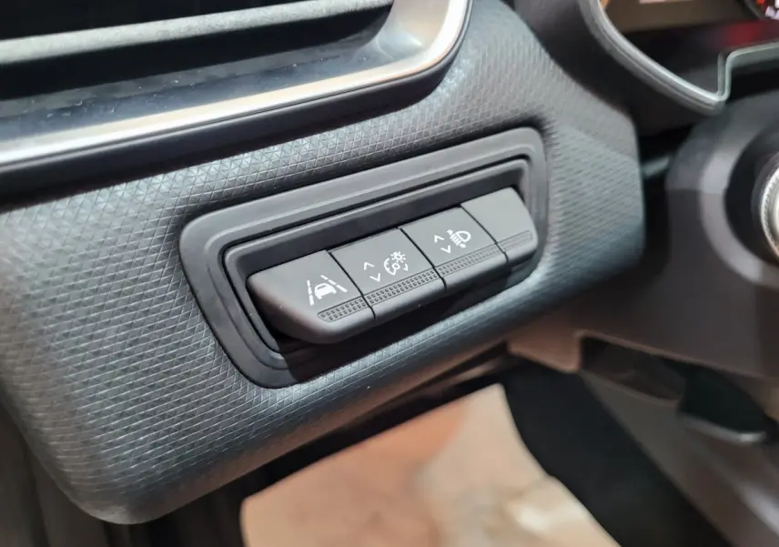 Gros plan sur les commandes d'assistance à la conduite sur tableau de bord noir de la Renault Clio Business blanche.