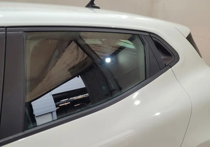 Détail de la vitre arrière côté gauche d'une Renault Clio Business blanche, soulignant la ligne de caisse fluide.