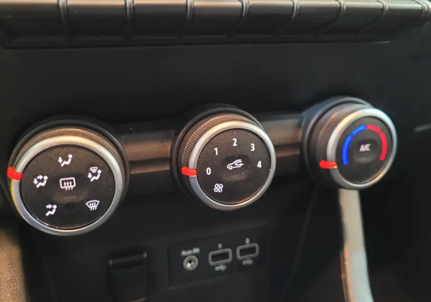 Gros plan sur les commandes de climatisation de la Renault Clio Business blanche, avec réglages ventilation et température.