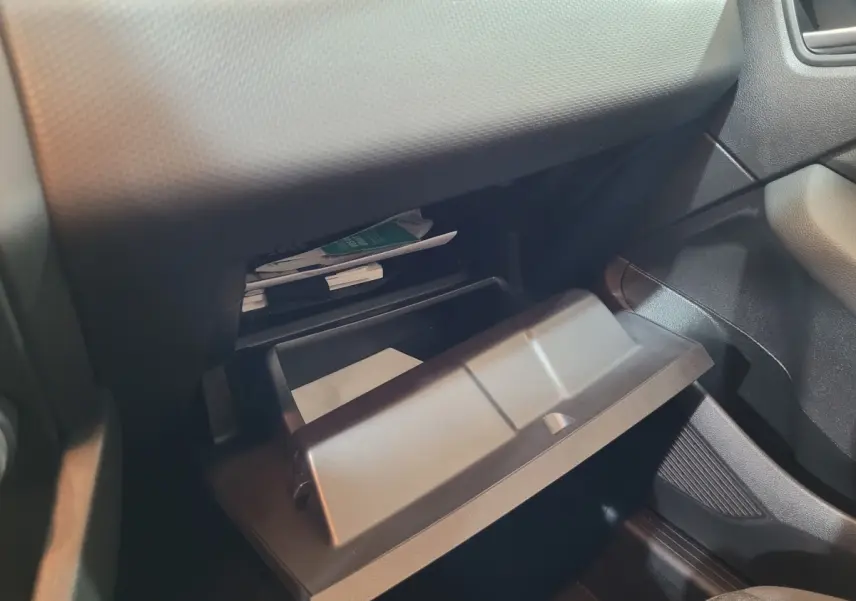 Gros plan sur la boîte à gants ouverte côté passager de la Renault Clio Business blanche, montrant des documents à l'intérieur.