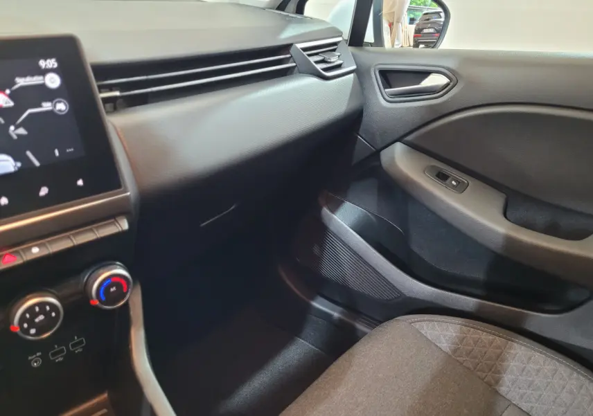 Vue intérieure côté passager de la Renault Clio Business blanche 2021, avec tableau de bord et commandes climatisation visibles.