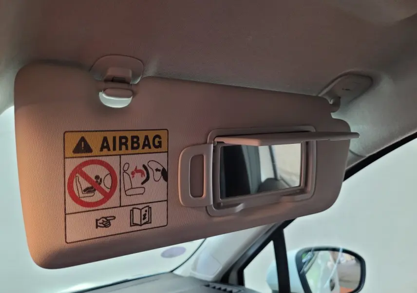 Détail du pare-soleil côté conducteur avec miroir et avertissement airbag dans l'habitacle d'une Renault Clio blanche.