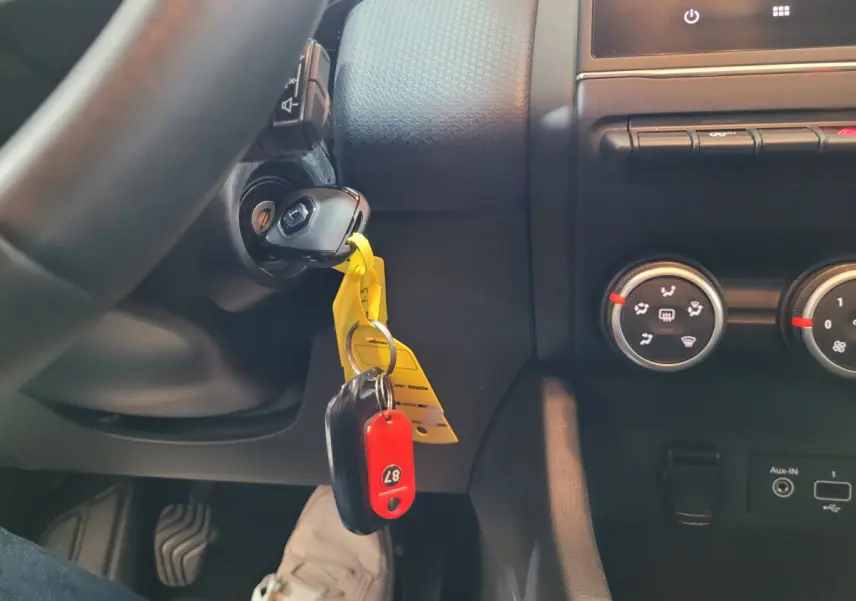 Gros plan intérieur sur le contacteur avec clé insérée et commandes de climatisation d'une Renault Clio Business blanche.