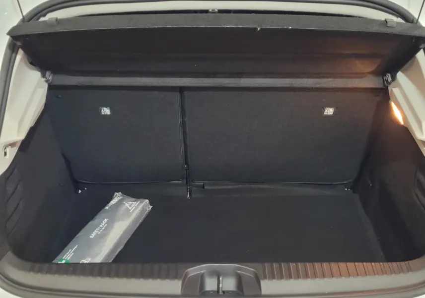 Coffre ouvert de la Renault Clio Business blanc, vue de l'arrière montrant un espace de chargement vide avec un kit de sécurité.