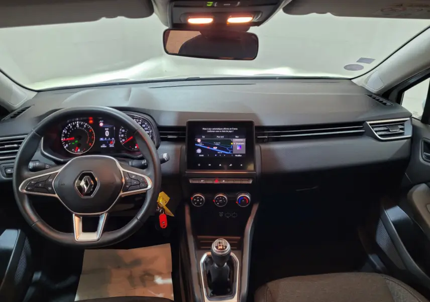 Vue intérieure avant du tableau de bord et volant cuir synthétique d'une Renault Clio Business blanche de 2021 avec écran tactile central.